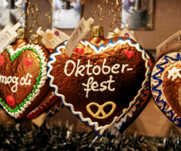 Drei dekorierte Lebkuchen in Herzform hängen an einem Oktoberfest Stand.