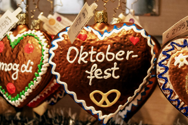 Drei dekorierte Lebkuchen in Herzform hängen an einem Oktoberfest Stand.
